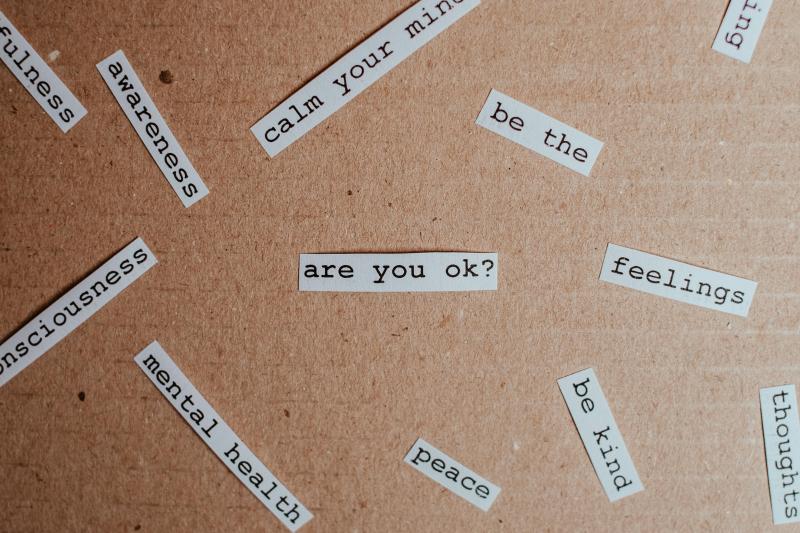 Phrases related to mental health, printed on white paper and cutout, on a craft paper background